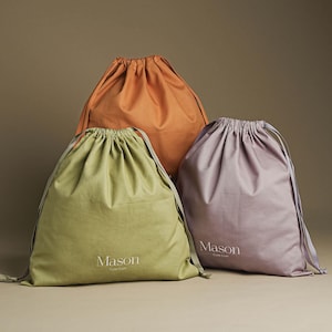 Può includere: Tre sacchetti con coulisse in diversi colori: arancione, verde e viola. Ogni sacchetto ha stampata la parola "Mason".