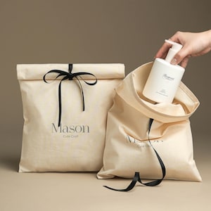 May include: Two beige fabric gift bags with black ribbon ties. The bags have the text "Mason Cute Craft" printed on them. One bag has a white bottle of hand soap inside.