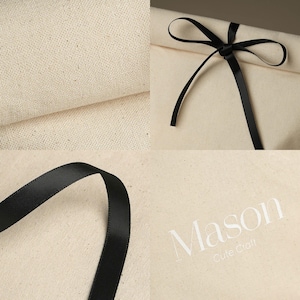 May include: A close-up of a natural canvas fabric with a black satin ribbon tied in a bow. The fabric has a subtle texture and the ribbon is smooth and shiny. The text "Mason Cute Craft" is printed in white on the fabric.