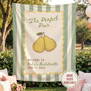 May include: A rectangular fabric banner featuring vertical sage green and white stripes. The center displays two yellow pears with the text "The Perfect Pair," "WELCOME TO Katie's Bachelorette," and "JUNE 17, 20XX" in a decorative yellow border.