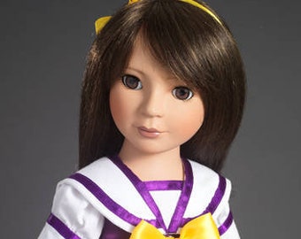 May include: A doll with long brown hair wearing a white sailor collar shirt with purple trim and a purple skirt with a yellow bow.
