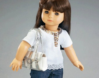 May include: A doll with brown hair wearing a white shirt with a lace trim, blue denim jeans, silver shoes, and a silver and brown purse.