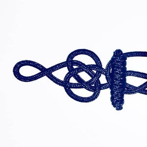 May include: A dark blue rope tied in a complex knot, creating a decorative design.