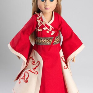 May include: A red and white doll dress with gold embroidery and a lion design. The doll is wearing a gold belt and has blonde hair and blue eyes.