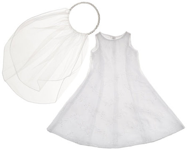 May include: White tulle dress with a white tulle veil and a silver headband. The dress has a sleeveless design and a full skirt.