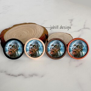 May include: Four round, zombie-themed decorative buttons with different colored frames: black, light wood, dark wood, and orange. Each button features a close-up of a zombie face with a snarling expression. The background is a light blue.