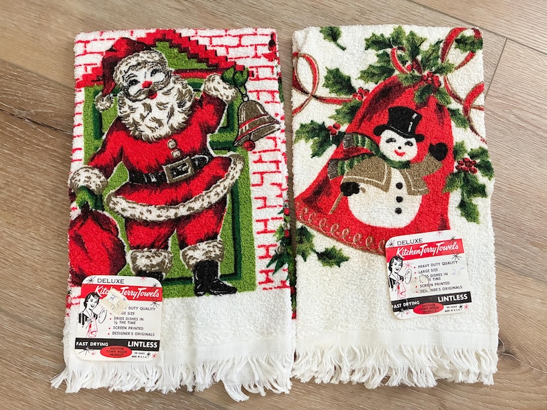 K&ouml;nnte beinhalten: Zwei Vintage-Weihnachts-K&uuml;chent&uuml;cher. Eines zeigt den Weihnachtsmann in einem roten Anzug mit Glocke und Sack. Das andere hat einen Schneemann mit Zylinder und Schal. Beide T&uuml;cher haben wei&szlig;e Fransen.
