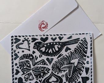 May include: A black and white linocut print of a bird, hearts, and leaves. The print is on a white background and has a black border.