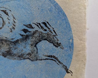 May include: An abstract illustration featuring a black horse silhouette in motion against a light blue circle. The artwork is on a textured, off-white paper, with visible edges and a vintage aesthetic.