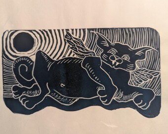 May include: Black and white linocut print of a cat with wings, lying on its side with its head turned to the viewer. The cat has a whimsical expression and a large, round moon behind it.