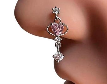 May include: A silver nose ring with a pink heart-shaped stone and clear crystal accents. The ring has a dangling charm with a clear crystal stone.