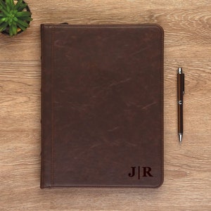 May include: A brown leather portfolio with a zipper closure and a monogrammed "J|R" on the front.