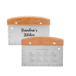 May include: Two stainless steel dough cutters with wooden handles. The top cutter has the text "Grandma's Kitchen" printed on it. The bottom cutter has a measurement chart in inches and milliliters.