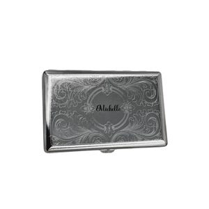 May include: Silver cigarette case with an ornate engraved design and the name "Michelle" inscribed in the center.