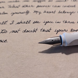 May include: A white fountain pen with a silver nib resting on a piece of paper with handwritten text. The text reads "Do not doubt that your love".