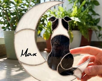 May include: Stained glass moon with a black and white dog silhouette, the name "Max" is written on the moon. The glass is white and the dog is black and white. The piece is hanging from a silver chain.