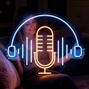 May include: A neon sign in the shape of a microphone and sound waves, with a blue outline and a yellow-orange interior. The sign is held by a person sitting on a couch. The sign has the word "Blselling" in the bottom right corner.