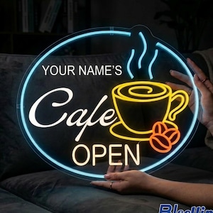 May include: A neon sign with a black background, featuring the words "YOUR NAME'S Cafe OPEN" in white and yellow. A yellow coffee cup with steam and orange coffee beans are also displayed. The sign is surrounded by a blue neon circle.