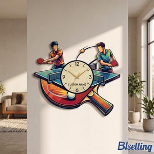 May include: A wall clock featuring a table tennis theme with two players, a ping pong table, and a paddle. The clock face is circular with gold hands, black numerals, and the text CUSTOM NAME printed in the centre against a light background.