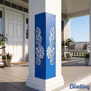 May include: A blue metal corner guard featuring a laser-cut monstera leaf pattern. The L-shaped panel is secured to the corner of a white porch column with visible screws at the top and bottom, displaying a vertical arrangement of foliage.