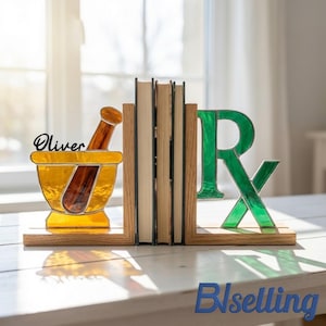 Gepersonaliseerde boekensteunen van gebrandschilderd glas met apothekersmotief, vijzel en stamper met aangepaste naam voor op de medicijnplank.