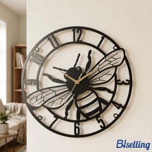 May include: Black metal wall clock featuring a bee design. The clock has Roman numeral hour markers and gold-colored clock hands. The bee's wings and body are intricately detailed.