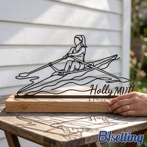 Puede incluir: Escultura de metal negro de una remera en un bote sobre una base de madera. La escultura presenta el nombre "Holly MVP" y una estrella. La escultura está sobre una mesa de madera.