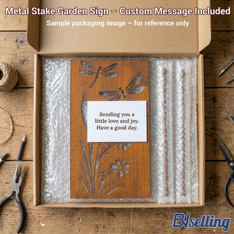 a wooden garden sign with a message, placed in a cardboard box with bubble wrap, and various crafting tools and materials are scattered around the box on a wooden surface.