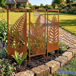 May include: Three rectangular metal garden trellises with a rusted finish, each featuring a laser-cut fern leaf design. The panels are mounted on stakes and positioned upright in a garden bed, showcasing intricate botanical silhouettes.
