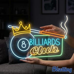 Può includere: Un'insegna al neon con una corona gialla, una palla numero 8 e le parole "BILLIARDS Club" in blu e giallo. L'insegna presenta anche una stecca e fumo. L'insegna è tenuta da due mani.