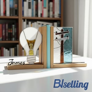 Puede incluir: Sujetalibros de madera con diseño de bombilla y poste telefónico. La bombilla es blanca con detalles dorados, y el poste telefónico es marrón y plateado. El nombre "James" está escrito en la base del sujetalibros.