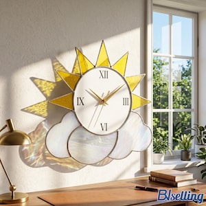 Pode incluir: Um relógio de parede com sol e nuvem, apresentando um mostrador circular branco com algarismos romanos pretos e ponteiros dourados. Os raios solares são de vidro colorido amarelo e as nuvens de vidro branco iridescente.
