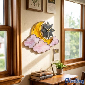 May include: A wall clock featuring a yellow stained glass crescent moon, pink marbled glass clouds, and a black star-shaped face with gold Roman numerals and hands. The clock is mounted on a wall between two wooden window frames.