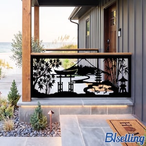 May include: A black metal railing panel featuring a laser-cut design of a Japanese landscape, including a torii gate, a pagoda, bamboo stalks, maple leaves, and a mountain silhouette, installed on a porch overlooking a coastal beach scene.