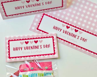 May include: Pink and white Valentine's Day gift set. The set includes a box, cards, and a bag of strawberry-flavored lollipops. The box and cards have a gingham pattern and the text "HAPPY VALENTINE'S DAY!" and "from kortlyn".