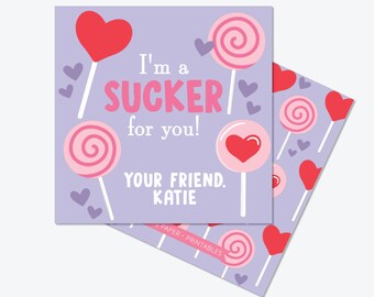 May include: A light purple Valentine's Day card with the text "I'm a Sucker for you!" and "Your friend, Katie." The card features red hearts and pink swirl lollipops. A second card is partially visible.