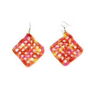 May include: A pair of crocheted earrings in a diamond shape. The earrings are made with a mix of orange, pink, and yellow yarn.