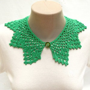 May include: A green crocheted collar with a button closure. The collar is made of delicate lace and has a scalloped edge.