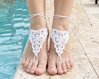 Può includere: Sandali a piedi nudi all'uncinetto bianchi. I sandali presentano un design triangolare che copre la parte superiore del piede, collegati da un cordino che avvolge la caviglia e tra le dita. Perfetti per matrimoni sulla spiaggia o eventi estivi.