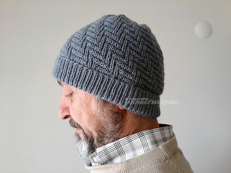 Puede incluir: Un gorro de punto gris con un patr&oacute;n de chevron. El gorro lo lleva puesto una persona con barba.
