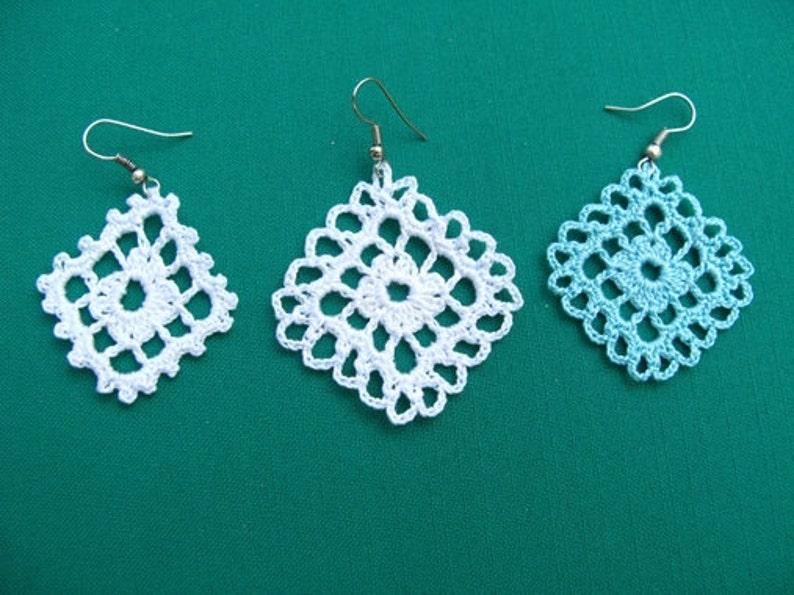 May include: Three pairs of crocheted earrings, two white and one light blue, with silver hooks.