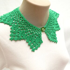 May include: A green crocheted collar with a button closure. The collar is made of delicate lace and has a scalloped edge.