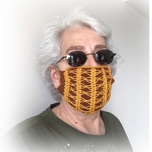 Pode incluir: Uma pessoa usando uma máscara facial de crochê marrom e dourada com óculos de sol.