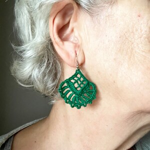 Puede incluir: Un par de pendientes de ganchillo verde con un dise&ntilde;o delicado e intrincado. Los pendientes son colgantes y tienen forma de l&aacute;grima.