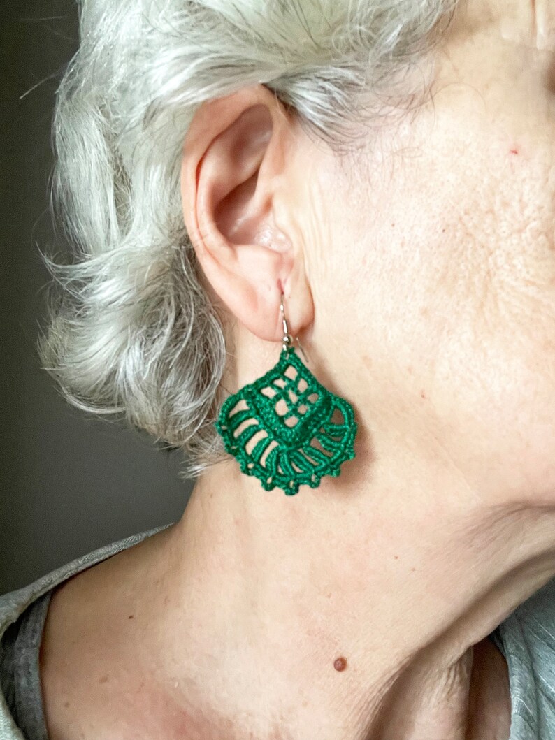 Puede incluir: Un par de pendientes de ganchillo verde con un dise&ntilde;o delicado e intrincado. Los pendientes son colgantes y tienen forma de l&aacute;grima.