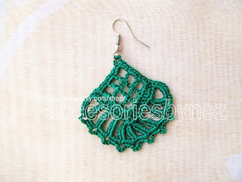 Puede incluir: Pendientes de crochet verde con un dise&ntilde;o delicado y de encaje. Los pendientes est&aacute;n hechos con un hilo fino y tienen un gancho plateado.
