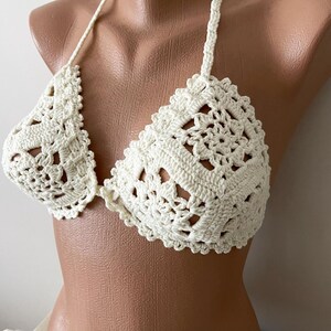 May include: A white crocheted bikini top with a delicate floral pattern.