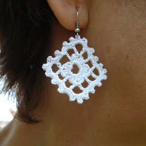 May include: White crocheted earrings with a square design. The earrings are attached to silver hooks.