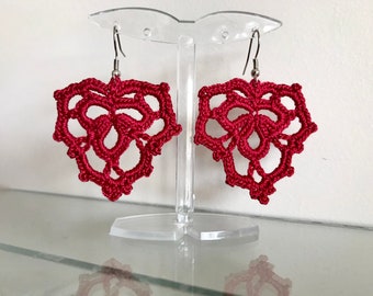 May include: A pair of burgundy crocheted earrings with a delicate floral design. The earrings are hanging from silver hooks.