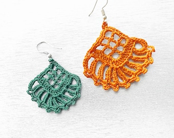 May include: A pair of crocheted earrings, one green and one orange, with silver hooks. The earrings are shaped like a teardrop and have a delicate, lacy design.